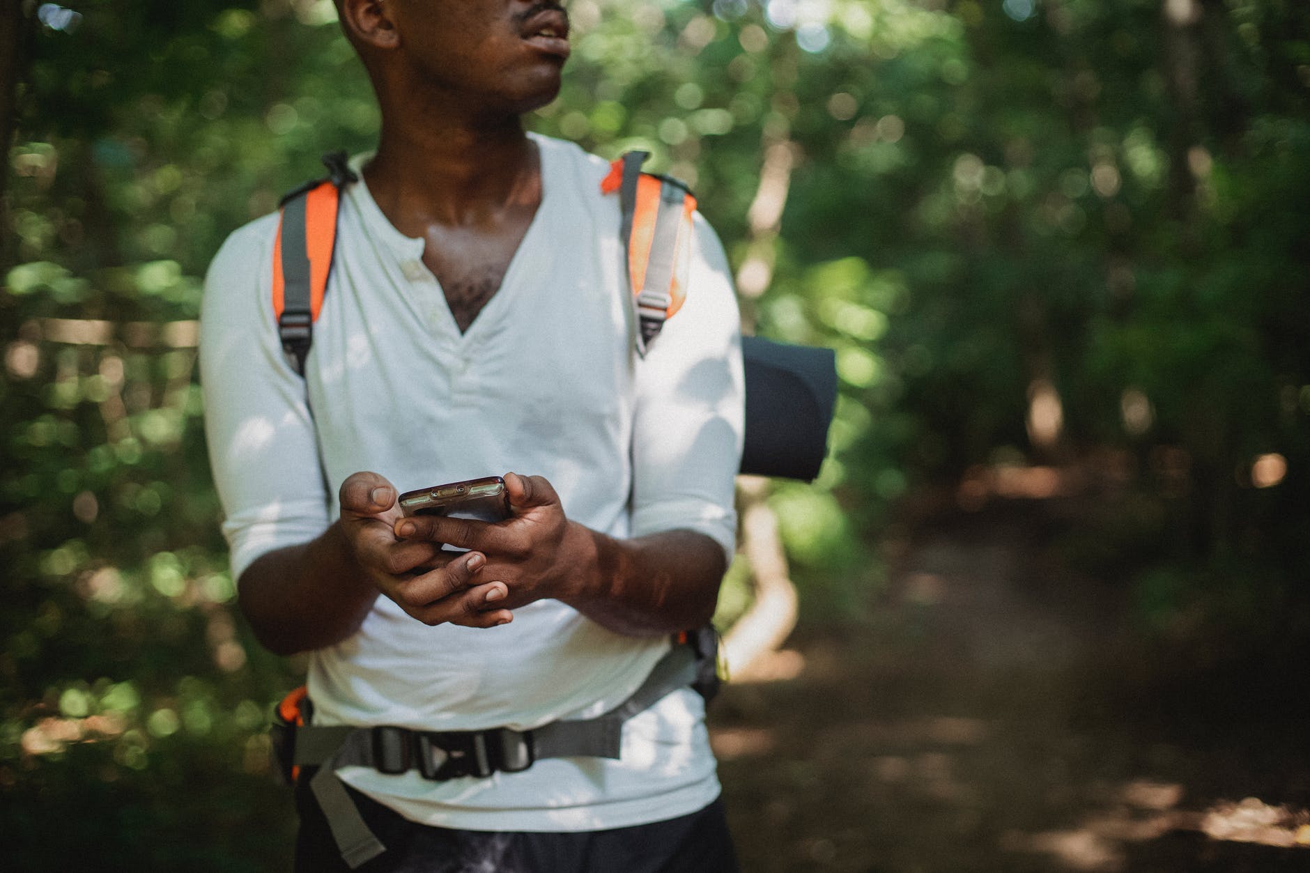 crop black man with backpack in forest