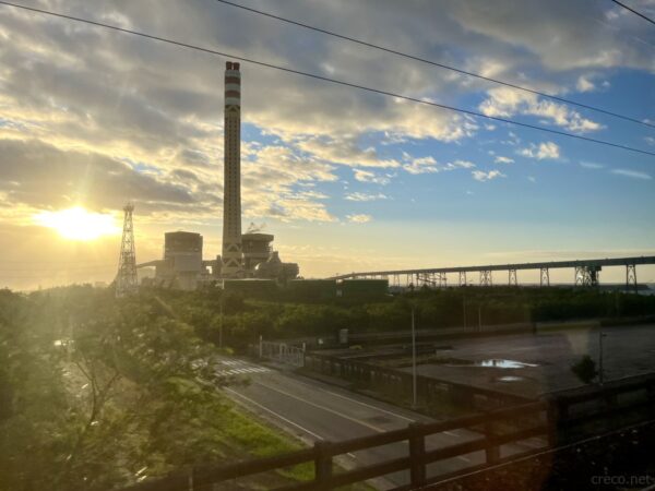 朝焼けに照らされる工場と海岸