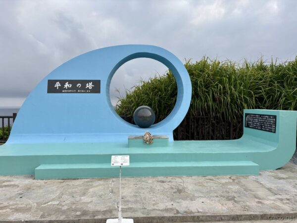 糸満市喜屋武岬「平和之塔」。水色の波形モニュメントに球体と鳩があしらわれ、沖縄戦戦没者を悼む慰霊碑が海を背に佇む。