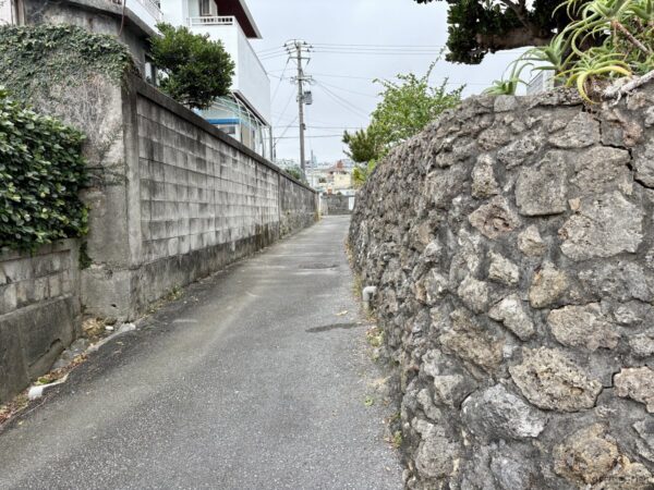 宮城島のコンクリブロック塀と石垣に挟まれた路地。電柱と赤瓦民家が連なる、昔ながらの沖縄離島の集落風景。