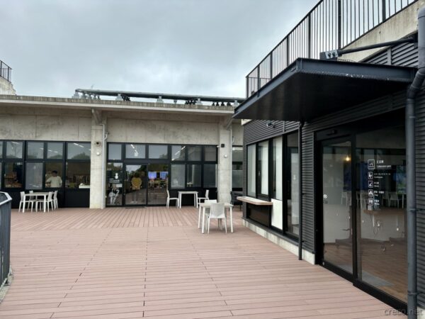 国頭村安波「やんばるパイナップルの丘 安波」のテラスデッキ。カフェのガラス張り店舗と屋外テーブル、やんばる観光の休憩施設。