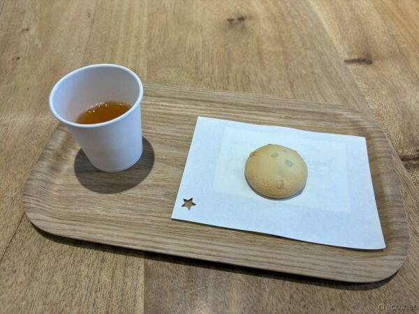 やんばるパイナップルの丘 安波のドリンクと焼き菓子。木製トレイに紙コップのお茶とヤンバルクイナ型のクッキー、素朴なカフェメニュー。