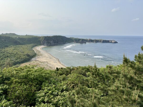 辺戸岬の断崖越しに広がる東シナ海。緑に覆われた岬と先端の島影、沖縄本島最北端の絶景パノラマ。