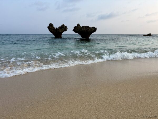 古宇利島ハートロックのクローズアップ。二つのハート岩が重なるように並ぶ、エメラルドの海に浮かぶ自然の造形美。