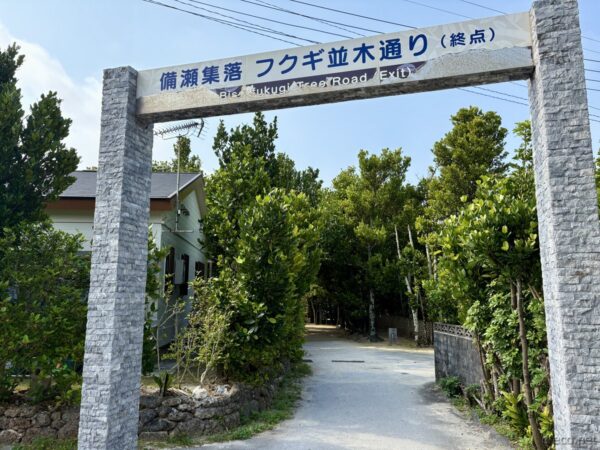 備瀬集落「フクギ並木通り」終点の石柱門。大きな看板「備瀬集落 フクギ並木通り（終点）」、散策終了のランドマーク。
