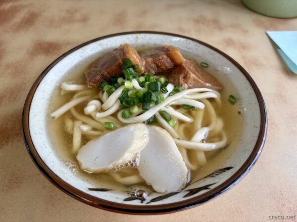 きしもと食堂の沖縄そば。手打ち太麺にソーキの角煮、カマボコとネギ、あっさりカツオだしの本部町名物。
