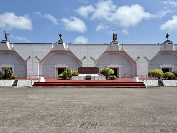 沖縄研修道場の中央アーチと赤絨毯階段。ブロンズ彫像がのる白いアーチ棟中央部、旧核基地を象徴する冷戦遺構。
