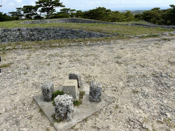 座喜味城跡の城郭跡に残る礎石。一の郭中央に組まれた建物跡、松と奥の石壁が背景の史跡景観。