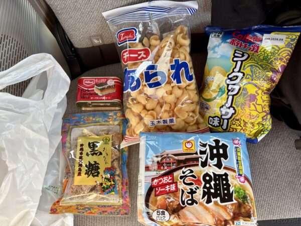 レンタカー車内でのお土産大集合。チーズあられ、ポテトチップスシークヮーサー味、マルちゃん沖縄そば、黒糖、沖縄旅の買い物成果。