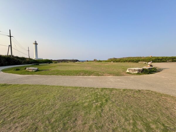 残波岬灯台とその手前の広場。夕陽が傾く時刻、白亜の灯台が立つ読谷村の岬の広大な草地。
