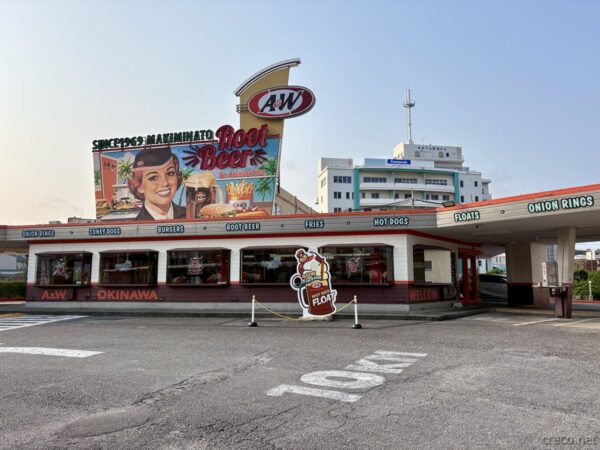 A&W牧港店の外観全景。赤と白のストライプ屋根、ネオン看板、ドライブスルーの白い屋根、1969年創業の沖縄の老舗ハンバーガー店。