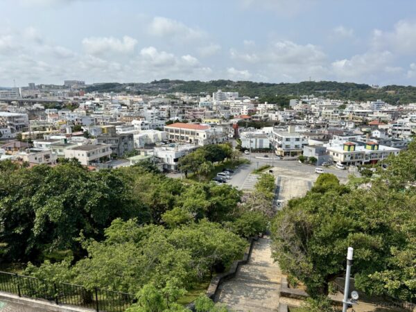 前田高地から見下ろす浦添市街。白い住宅群と丘陵地、沖縄の現代都市風景、ハクソーリッジからのパノラマ。