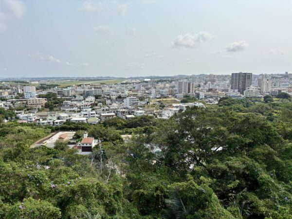 前田高地から那覇国際空港方面を望む。遠くに滑走路と街並み、沖縄戦時の激戦地から見る平和な現代沖縄。