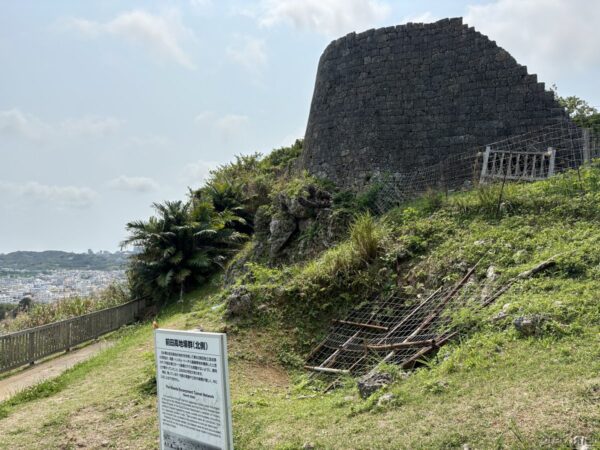 浦添城跡北側の再建された石垣。円錐形の城壁と芝地、足場が組まれて修復中の中山王国時代の城郭遺跡。