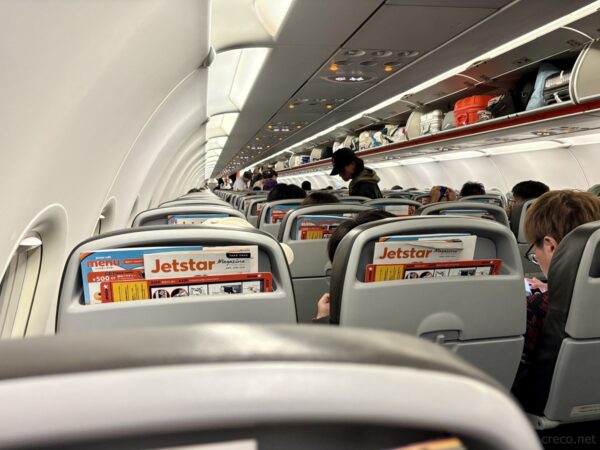 ジェットスター機内の通路。座席のポケットに入ったJetstar機内誌、沖縄から本土へのLCC帰路の機内風景。