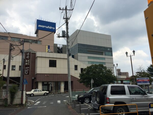 東飯能駅前から見上げる丸広百貨店飯能店、屋上の青いmaruhiro看板が目印