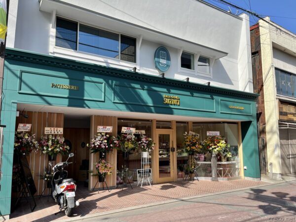 リニューアルオープンした夢彩菓すずき、緑色の店構えと開店祝いの花籠が並ぶ店先