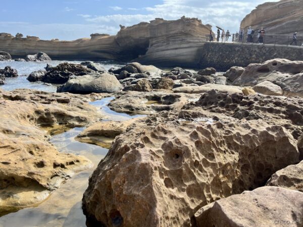 海岸の岩盤、波食棚を歩く観光客