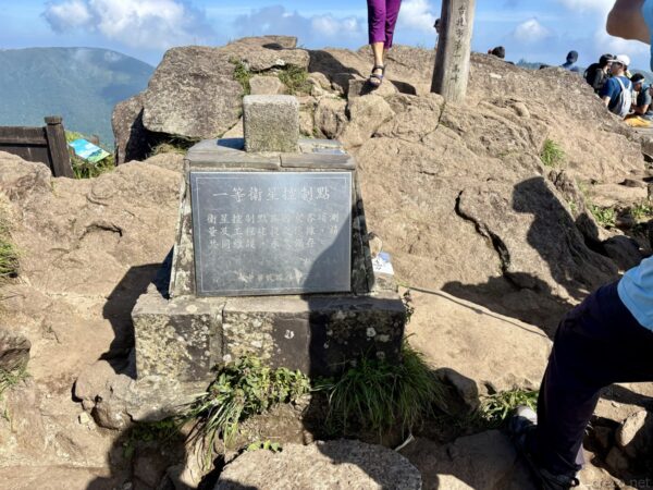 七星山山頂付近にある「一等衛星控制點(一等三角点)」の石標。岩場に据えられた石造りの標石に説明文が刻まれ、周囲では登山者が行き交っている。
