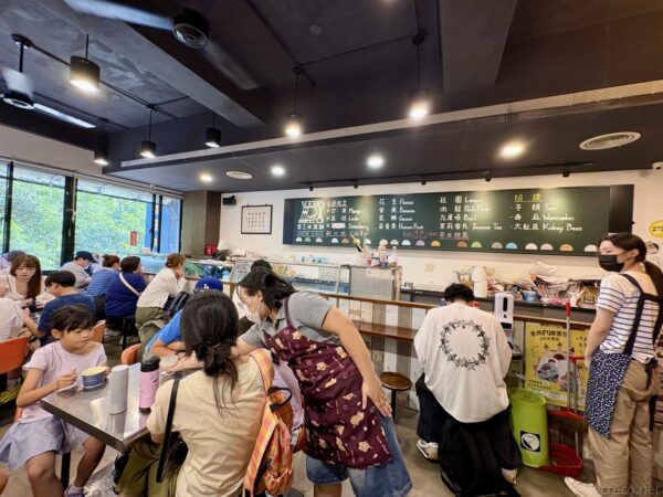 雪王冰淇淋の二階店内。黒板メニューを背にした対面式のカウンターに、家族連れや客が並び、アイスを注文する賑わいの光景。