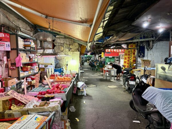台北・城中市場の一角を見上げた一枚。テントの屋根や店の看板、吊り下げられた照明が並ぶアーケードで、「老牌牛肉拉麵大王」の赤い看板も見える薄暗い市場の様子。