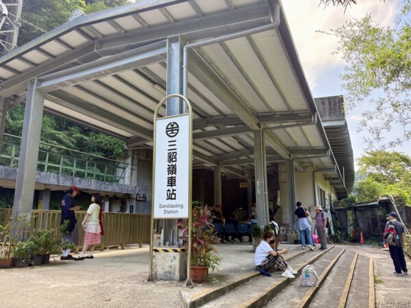 三貂嶺（Sandiaoling）站の駅舎。「三貂嶺車站 Sandiaoling Station」の看板を掲げた簡素な建物の前に、鉢植えや観光客が写る山あいの駅。