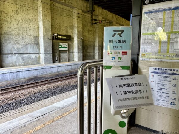 駅の自動改札機と「刷卡進站 TAP IN」の案内。「尚未開放進站」の貼り紙があり、まだ開放前の様子。壁に路線図が掲示されている。
