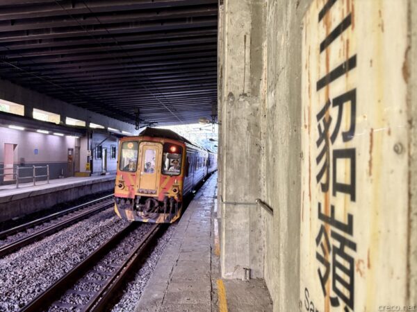 三貂嶺駅の薄暗いホームに停車する橙の旧型列車。右手のコンクリート柱に「三貂嶺」と大書され、複線の線路が奥へ延びる。