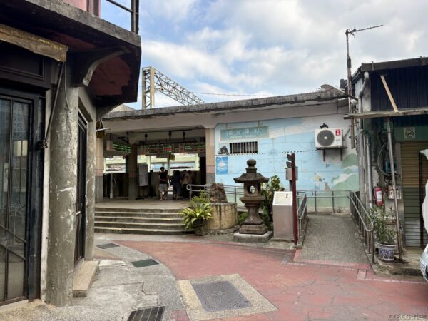 瑞芳駅の出入口付近。改札へ続く階段のある駅舎入口の脇に、青い海や鳥を描いた壁画と石灯籠が置かれ、古い建物に挟まれた通路になっている。
